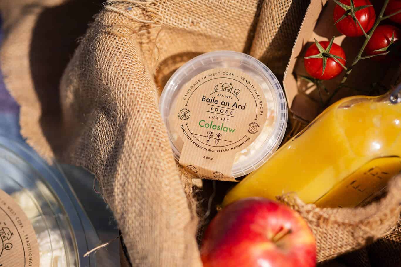 Basket with coleslaw, tomatoes, juice, and apple.