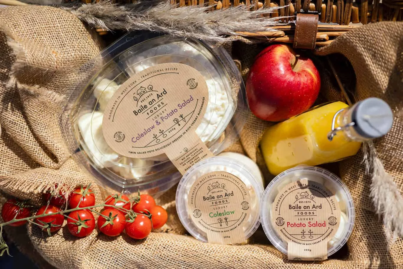 Picnic basket with Baile an Ard Foods coleslaw and potato salad, tomatoes, apple, and orange juice.